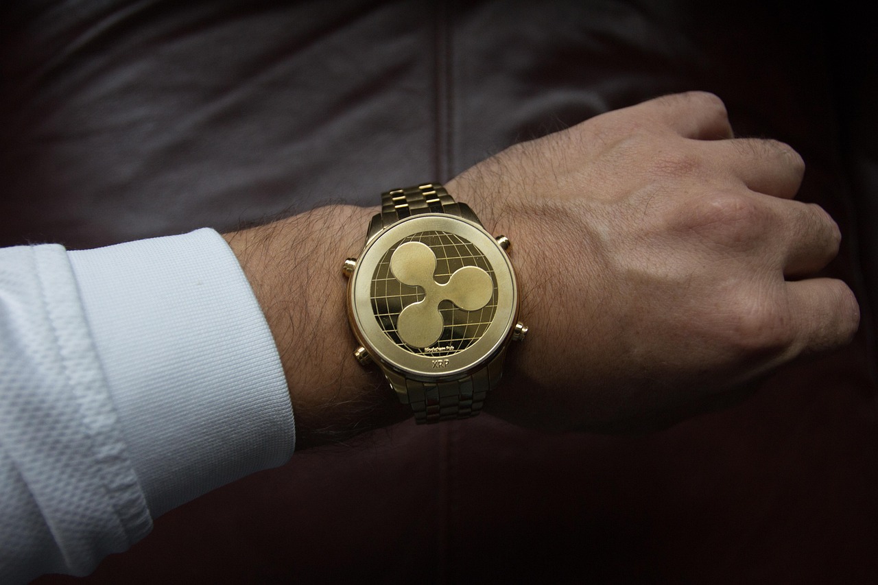 Eine Armbanduhr getragen an der linken Hand. Statt einem Zifferblatt zeigt die Armbanduhr das Logo der Kryptowährung Ripple. Ein Hinweis auf die Möglichkeit, dass unter Präsident Trump die Kryptowährung Ripple (XRP) Teil der strategischen Reserve wird.